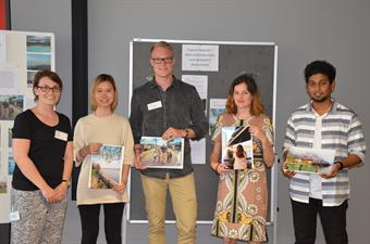 A representative of the International Office and 4 winners of the photo contest 2017 are looking into the camera and showing their photos.
